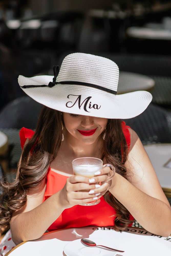 15 years old girl posing for pictures in Parisian café with personalized hat saying MIA