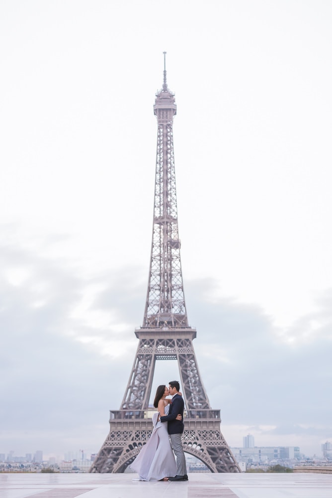 Asian bride and groom kissing in the middle of the Eiffel Towerr