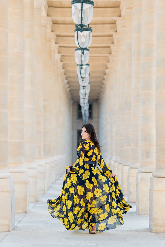 Beautiful girl dressed in yellow running between the columns of Palais Royal in Paris