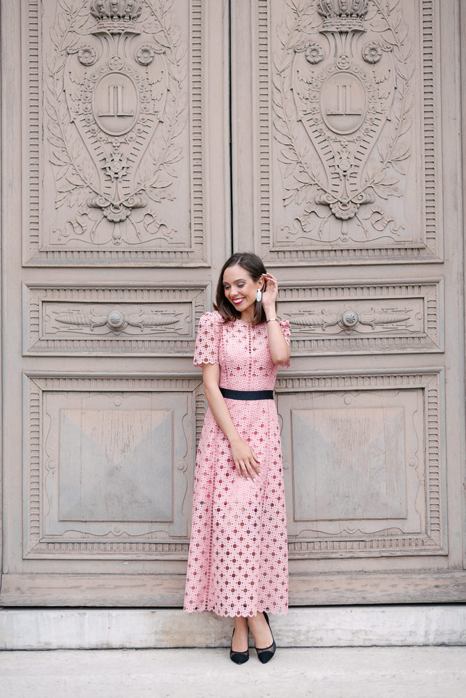 Beautiful girl in pink dress posing in front of old door in Paris