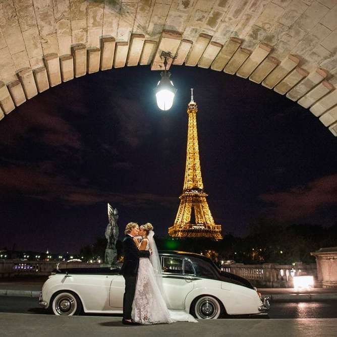 best photography spots in Paris bride and groom kissing in front of white vintage rolls royce on the bir hakeim bridge