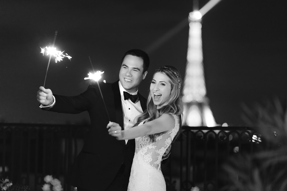 Bride and groom holding sparklers with the Eiffel Tower in the background on a Paris wedding