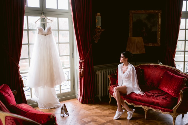 Bride looking at her wedding dress before getting ready for ceremony in Chateau de Villette