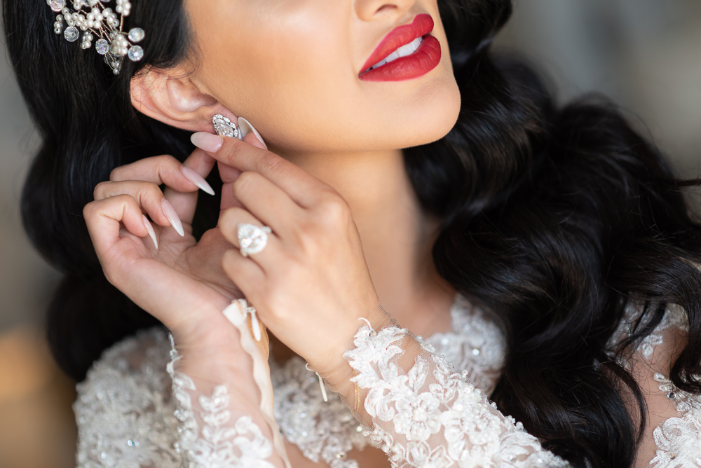Close-up of bride wearing bridal make-up putting on diamond earrings