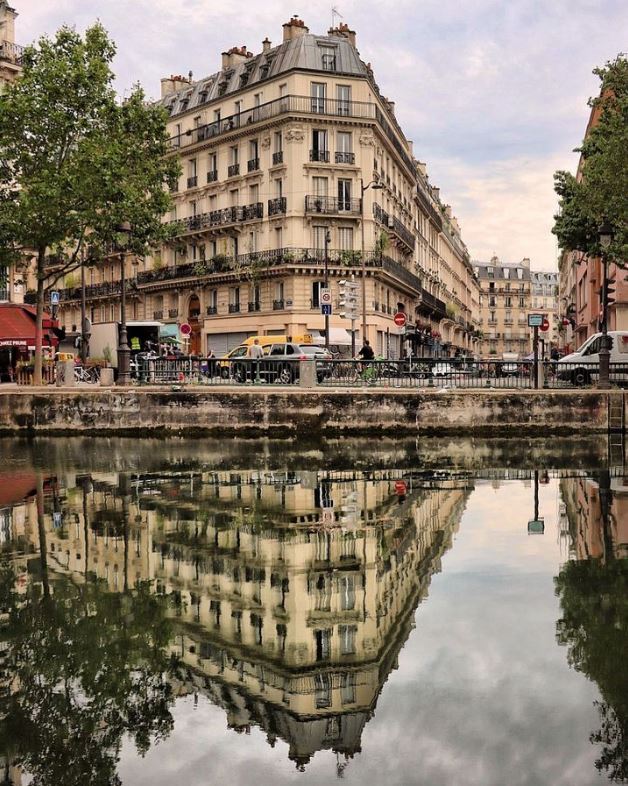 View from one bank of Canal Saint Martin in Paris with building mirroring in water