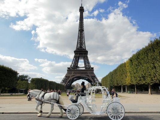 man with white horse and white carriage in front of Eiffel Tower in Paris