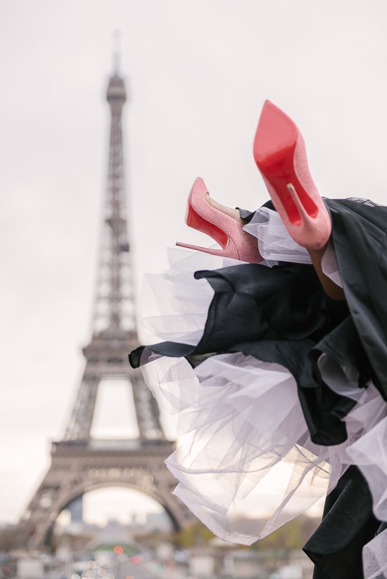 Christian Louboutin red soles lifted in the air at the Eiffel Tower in Paris