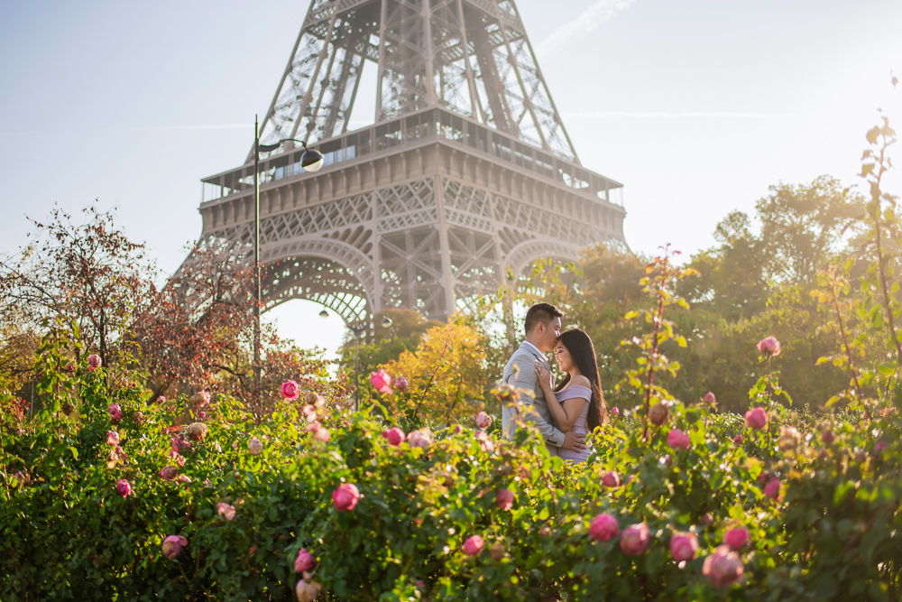 Couple kissing in the sunshine surrounded by beautiful roses and the Eiffel Tower