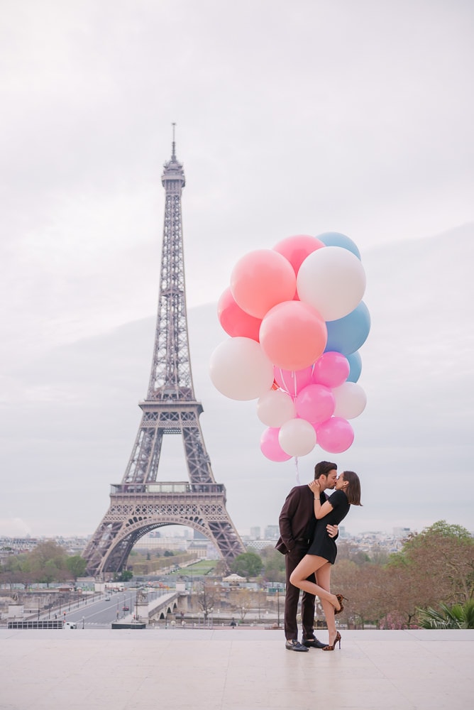 Crazy couples pictures - Young couple kissing underneath huge and colorful balloons in Paris