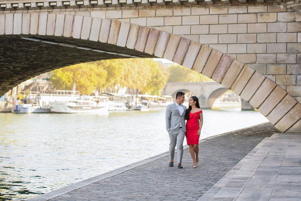 Elegant couple walking along the Seine river under the Louis Philippe bridge
