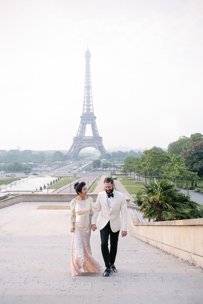 engagement photo paris of a couple walking up steps from eiffel tower