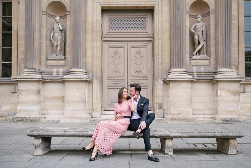 Engagement picture dresses - Girl in pink long dress being hugged by her fiancé in front of old door at the Louvre Museul in Paris