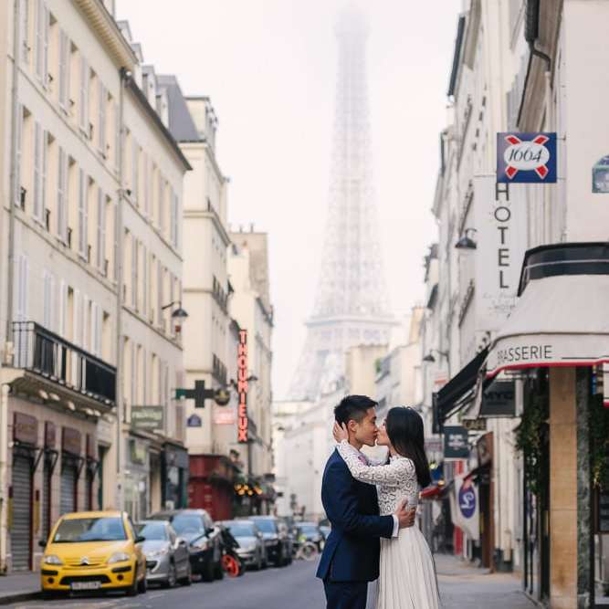 Girl kissing boy in a street overlooking the Eiffel Tower