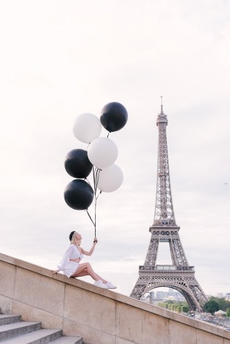Girl with black and white balloons posing at Eiffel Tower