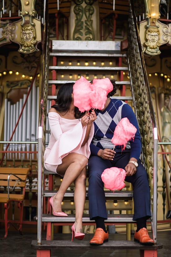 Girl with pink Louboutin heels kissing her boyfriend behind candy floss on the merry go round near Eiffel Tower