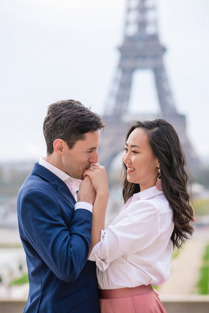 Man kissing fiancees hand after proposing in Paris