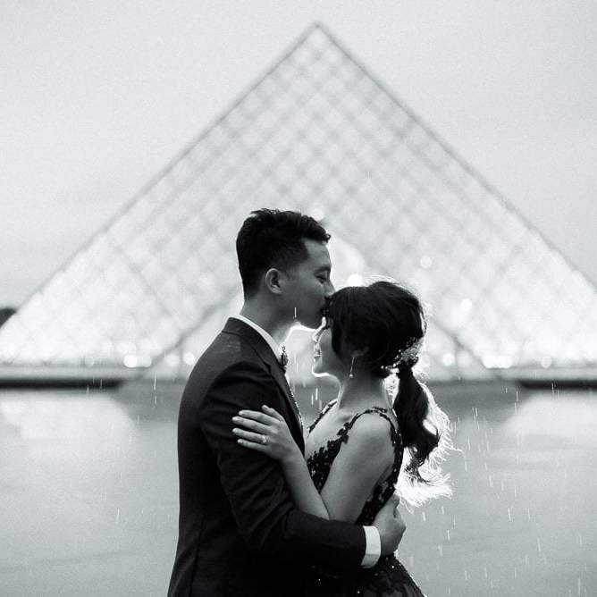 most romantic spots in paris - louvre museum cute asian couple kissing in the rain