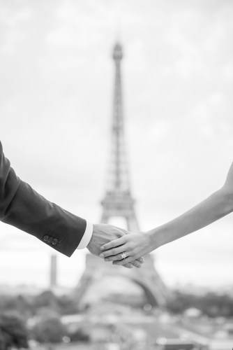 Newly engaged couple holding hands in front of the Eiffel Tower for their engagement pics