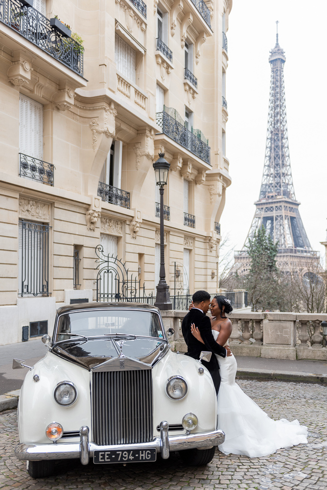Newly married couple posing for wedding photos with vintage car at the Eiffel Tower