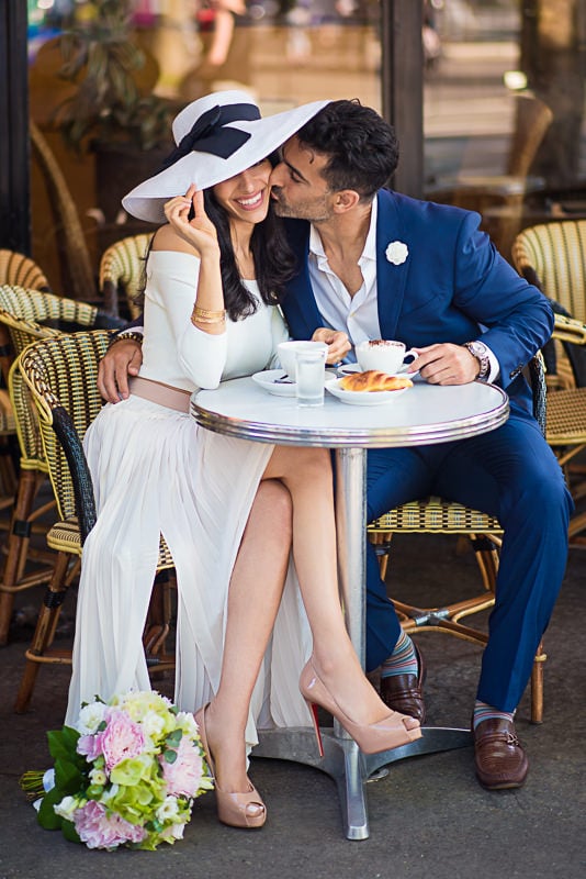 Handsome gentleman kissing his fiancée on the cheek in a parisian café