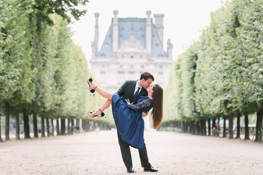 Paris engagement photographer - gentleman in a suit dipping and kissing his fiancée in the tuileries gardens in Paris