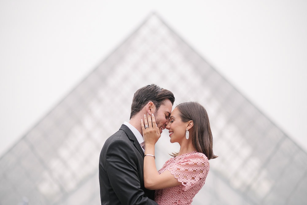 couple kissing with the Louvre glass pyramid in a blurred background