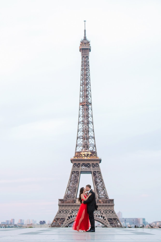 woman in a red dress kissing a man with Eiffel Tower in the background