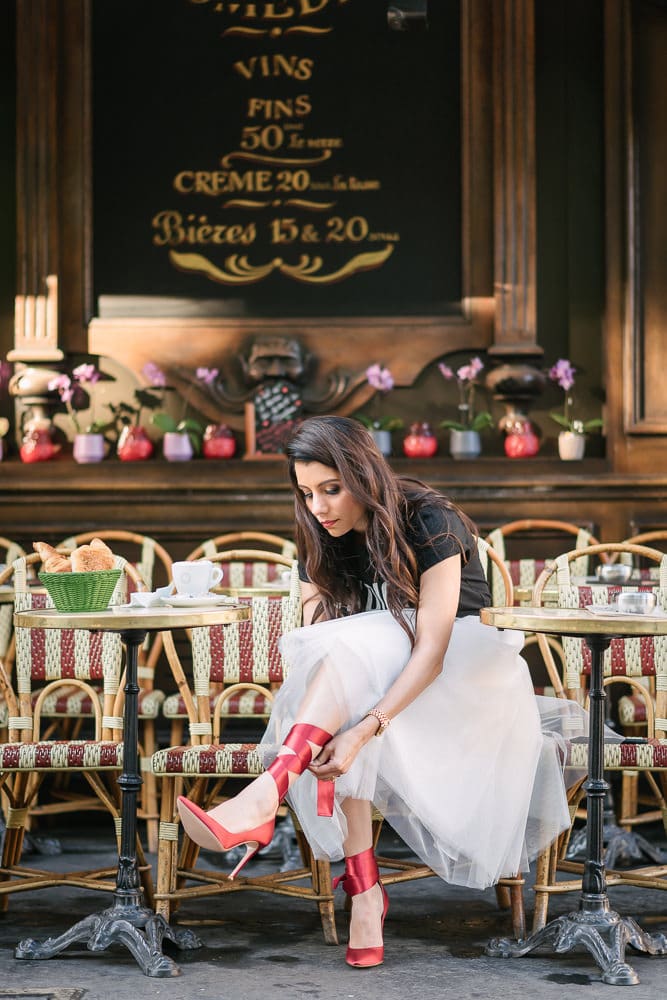 Paris portrait of a girl putting her red heels on in a Parisian cafe
