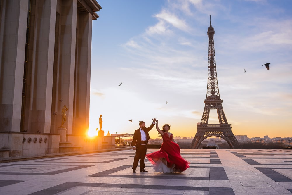 paris prewedding photographer capturing bride in red dress dancing at sunrise in front of the eiffel tower