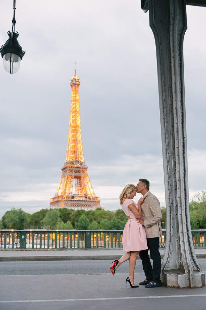 Woman wearing Louboutin shoes and pink dress is kissed by husband in Paris