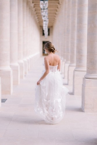 Young girl dressed in wedding dress posing for portraits in Paris by the Palais Royal